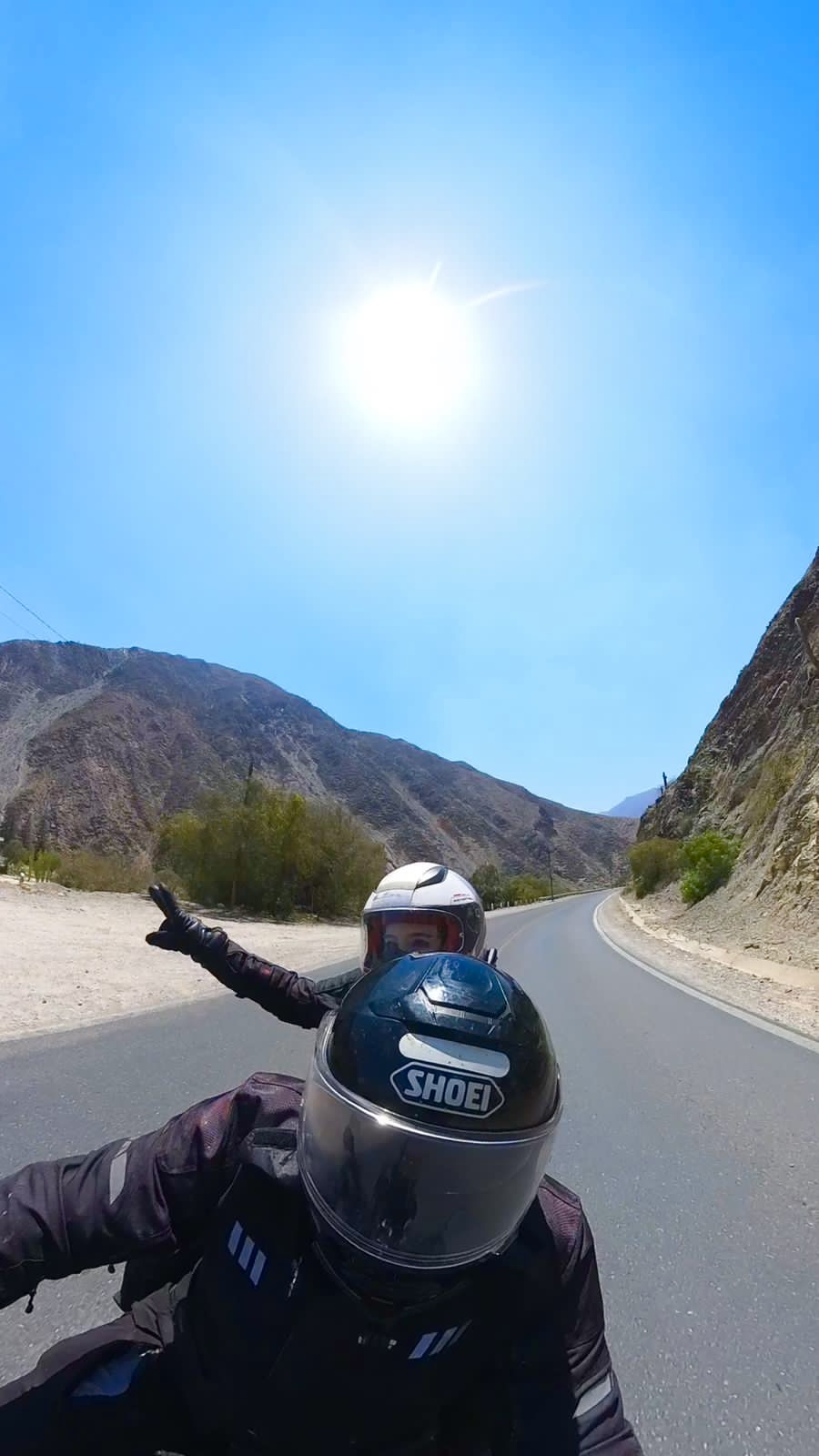 Selfie de capacete em uma estrada de montanha ensolarada