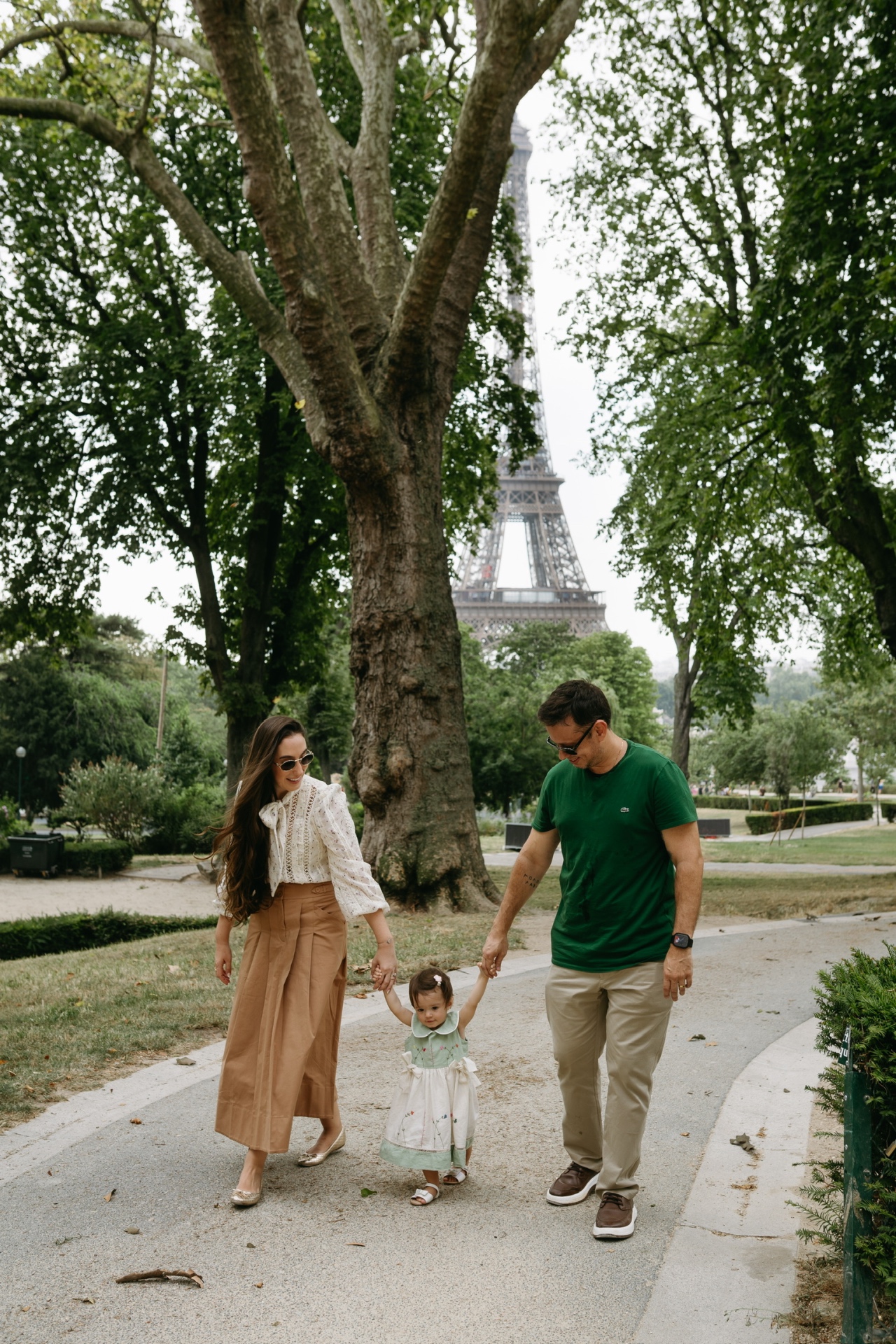 Nós três caminhando de mãos dadas em Paris com a Torre Eiffel ao fundo