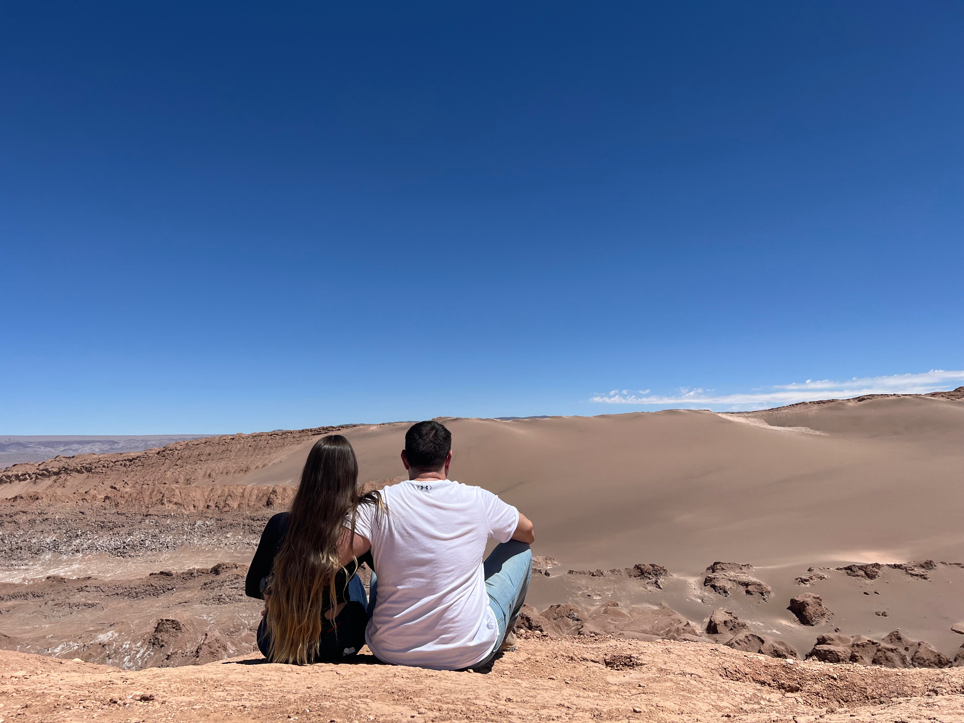 Gabriela e Marcelo sentados olhando dunas no deserto do Atacama